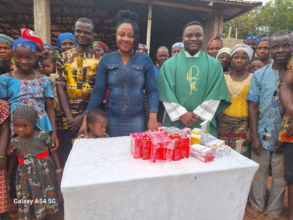 Nurse Vivian Okafor and the parish priest with the community they served, gathered behind a table of donated medicines